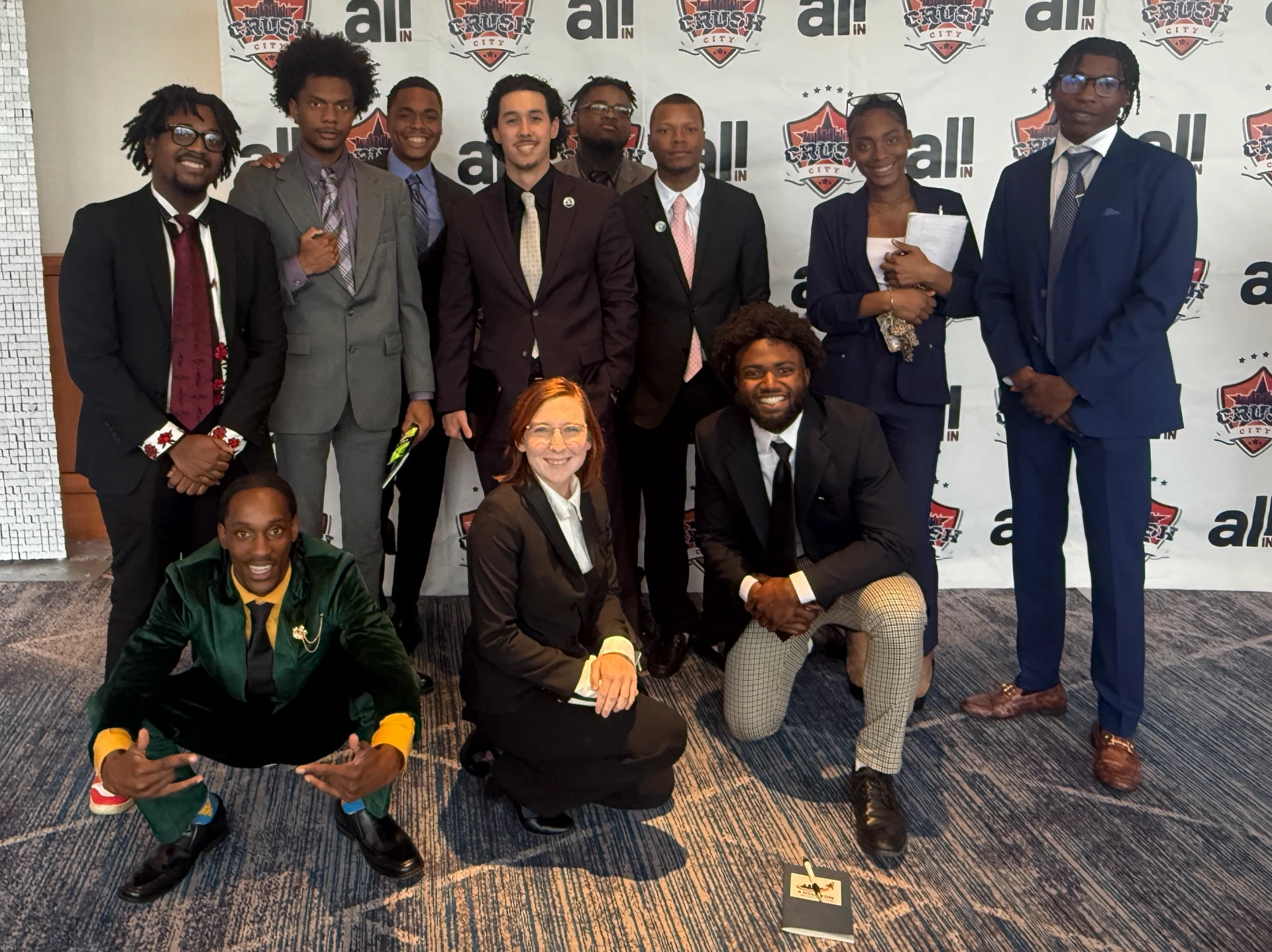Group of individuals posing together at a branded event backdrop.